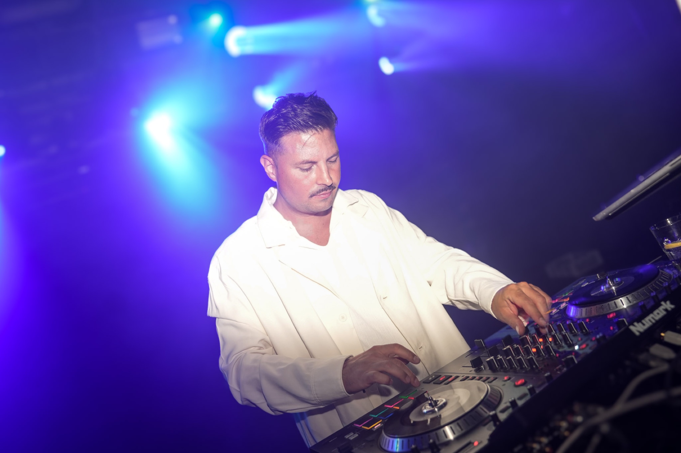 DJ Raff live am Mischpult in intensivem blau-violettem Clublicht