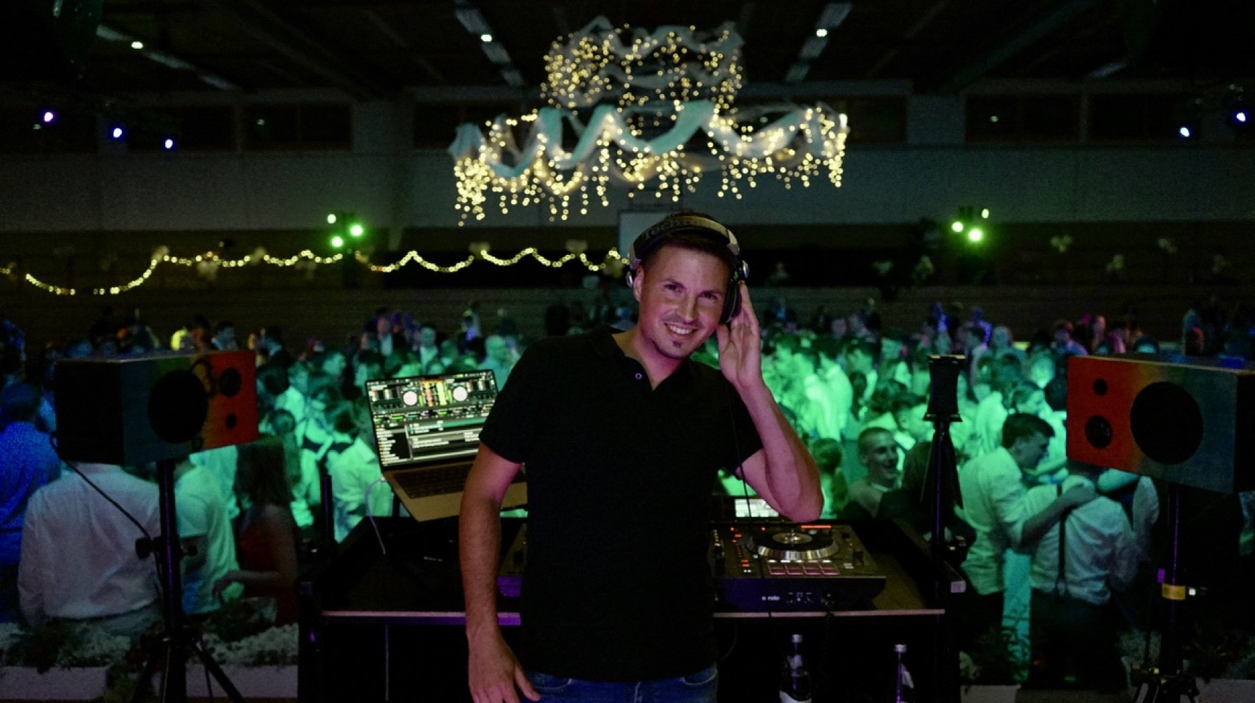 DJ Raff vor einer großen, beleuchteten Tanzfläche